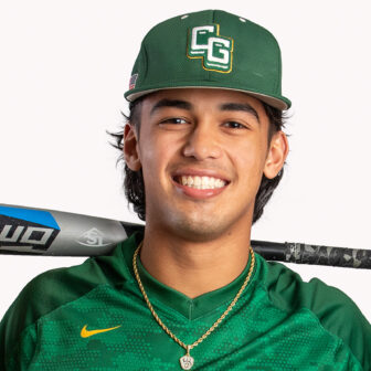 Smiling male baseball player in green hat, and green jersey with a baseball bat behind his neck.
